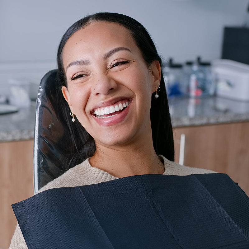 Smiling female patient sitting in a dental chair during a routine dental appointment, showing comfort and confidence after receiving professional dental care.