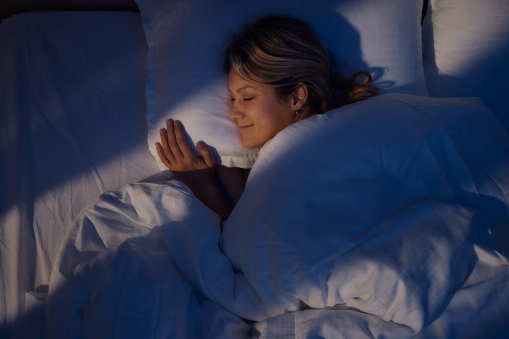 A woman sleeps peacefully in bed, representing a comfortable and restful sleep after sleep apnea surgery.